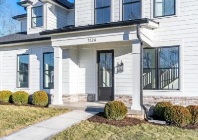 Front view of a white, modern two-story house with a covered entry, black front door, and neatly trimmed shrubs by a concrete walkway (address 3524).