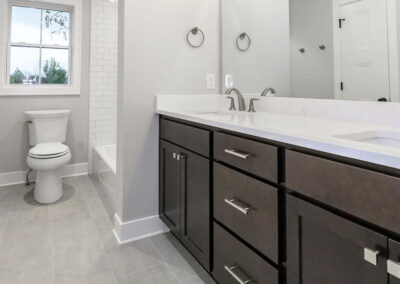 Modern bathroom with a double-sink vanity, dark wood cabinets, and a large mirror above a white countertop.