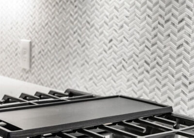 Cast iron griddle resting on a gas stove with a chevron-pattern backsplash in a modern kitchen